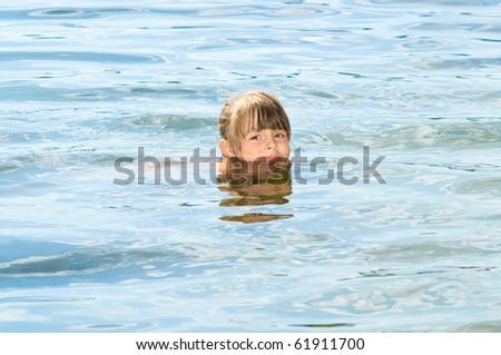 pleasure beautiful little girl swim in blue water, lean out of water  and smile