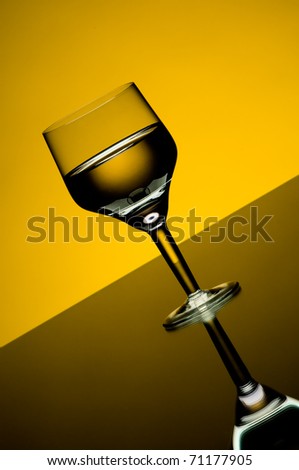 the beautiful wine glass with  beverage,  standing on mirror, yellow light