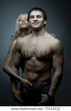 muscular handsome sexy guy with pretty woman, on dark background, glamour blue light, guy look on camera and smile