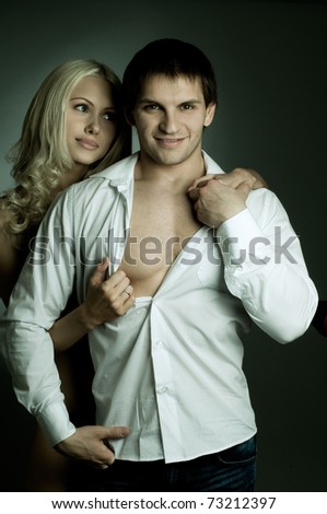 muscular handsome sexy guy with pretty woman, on dark background, glamour light, guy look on camera and smile