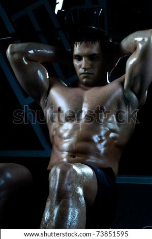very power athletic guy ,  execute exercise on muscles belly, in  sport-hall, beauty glamour blue light