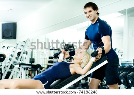 happy cutie athletic girl and guy,  exercise with dumbbells and smile, in  sport-hall