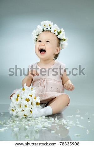 beautiful  little kid with  bouquet and diadem of flowers , sit and  smile
