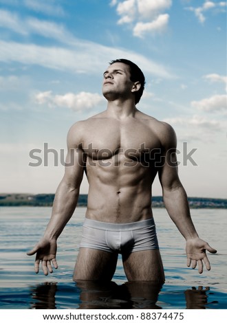 the very muscular handsome sexy guy on sky and sea background
