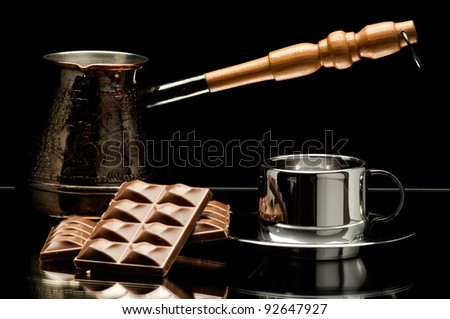 still life on mirror, coffee pot with polished surface steel  noggin and chocolate, on dark background