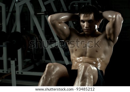 very power athletic guy ,  execute exercise on muscles belly, in  sport-hall, beauty glamour light