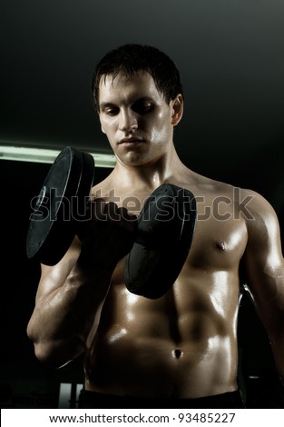 very power athletic guy ,  execute exercise with  dumbbells, in  sport-hall, beauty glamour light