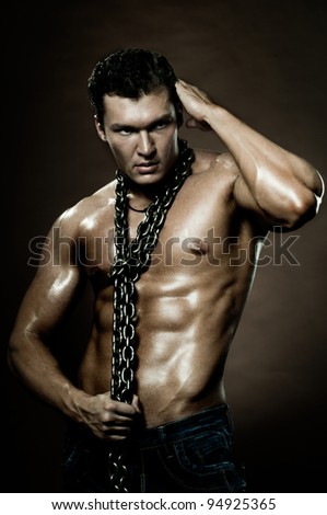the very muscular handsome sexy guy on dark  brown background, with neckcloth of  chain on neck