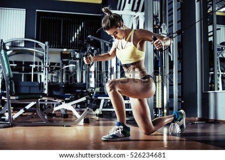 young fitness woman execute exercise with exercise-machine Cable Crossover in gym, horizontal photo.