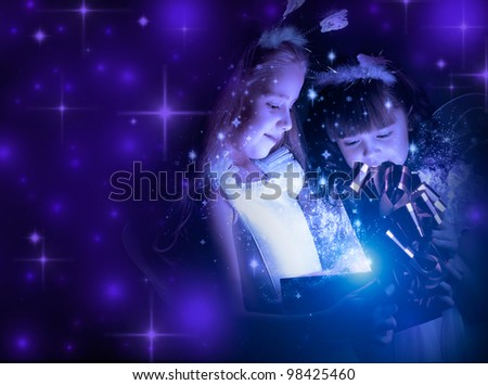 two little girl examine gift in fancy box, smile, on dark blue background