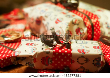 Lots of of Christmas gifts in a variety of packaging. White with penguins and red with white polka dots wrapping paper, as well as cakes in transparent cellophane.
