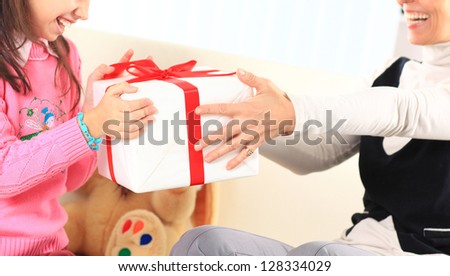 Little beautiful pretty girl giving a gift to her happy mother