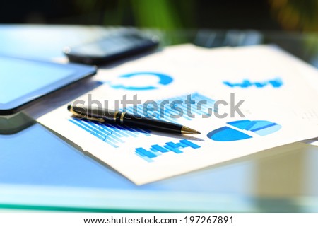 Financial charts on the table with tablet and pen