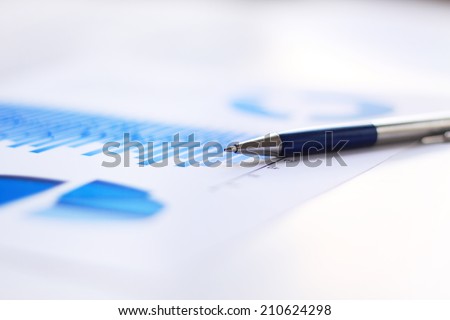 A closeup of a business financial chart with bar and pie graphs. A pen is on top. Can be used to represent business expenses, growth or revenue.