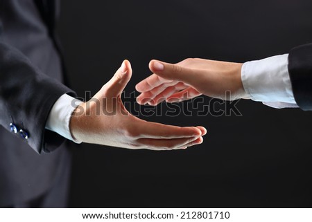 Photo of hands of business partners before handshake in black background