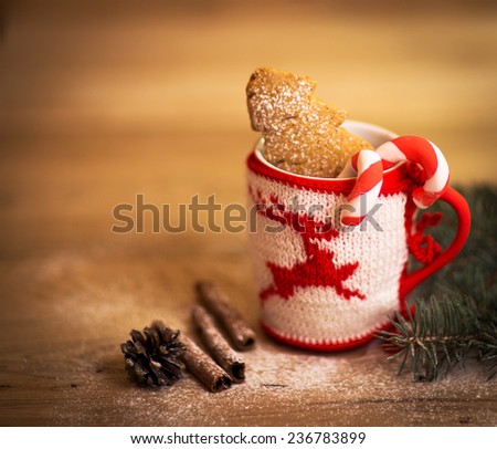 Christmas mug with decorations and sweets on wooden background