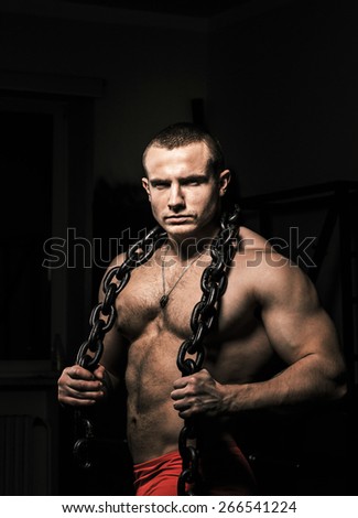 Muscular strong male  poses holding steel chain