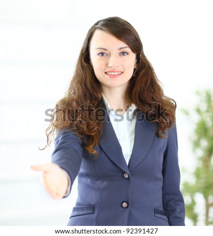 A beautiful young smiling business woman, happy and smiling , with an open hand ready to seal a deal or saying welcome.