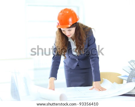 Beautiful businesswoman, an engineer with the work plan, standing in the office.