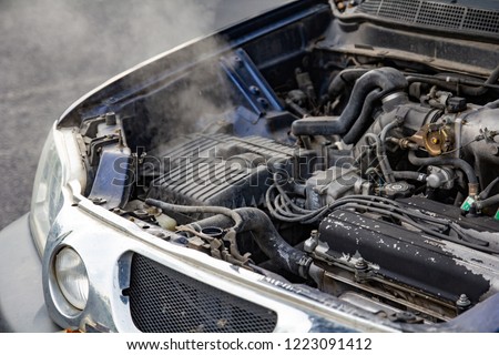 Car engine over heat with no water in radiator and cooling system.\
Overheated car machine Broken down with smoking, overheating engine on the road.\
Automotive motor problem concept.