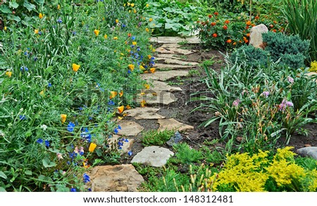 A stone walkway winding its way into the the garden beside the flowers