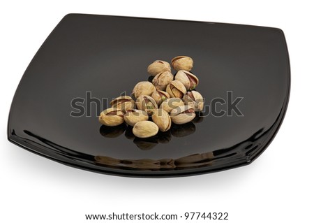 Salted shelled roasted pistachios on a black plate.