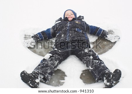 A child smiles as he has the time of his life making snow angels in the snow.