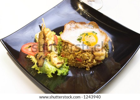 Exotic dish of Indonesian fried rice made with chicken and shrimp, topped with a fried egg. Chicken and beef satays are served on the side.
