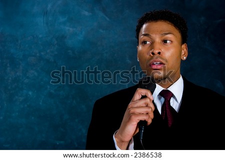 An African American man in a business suit makes a speech.