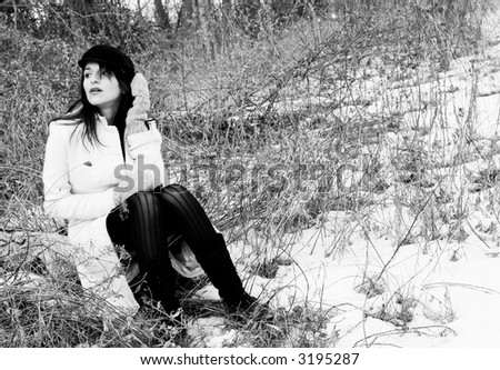 Woman sitting in the woods in the dead of winter. Artistic black and white
