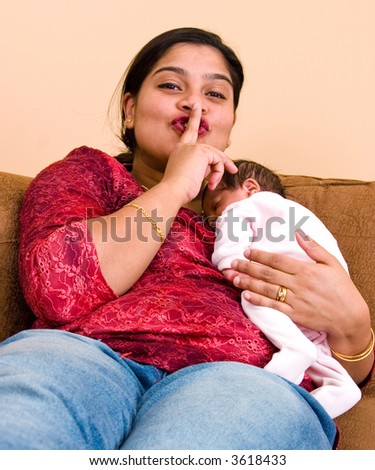 A young mother gestures for some quiet time as her baby sleeps