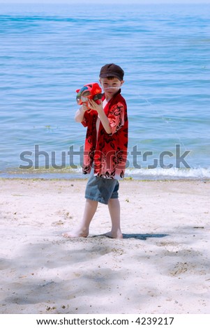 A boy on the beach with his water gun