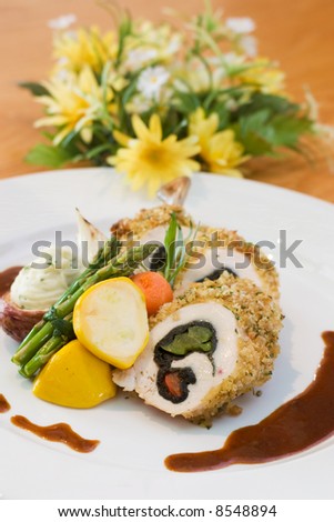 Breaded chicken slices stuffed with sweet peppers and served with asparagus and vegetables