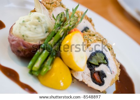 Breaded chicken slices stuffed with sweet peppers and served with asparagus and vegetables