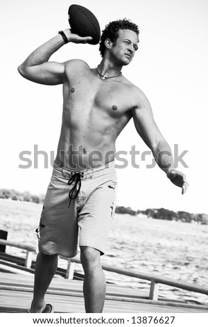 A young man throws a football at the beach