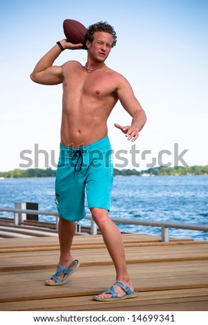 A young man throws a football at the beach