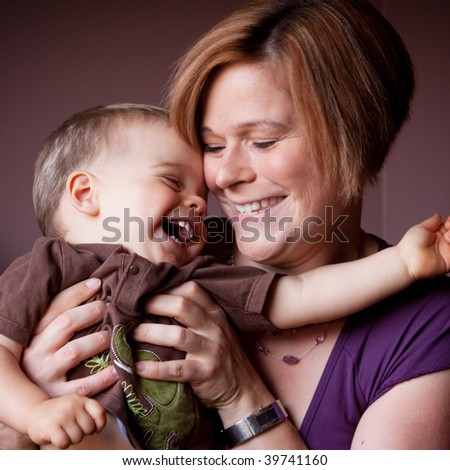 A caucasian mother tickles her child as he giggles uncontrollably