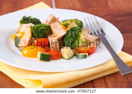 Healthy vegan meal of spiced Tofu and vegetables such as broccoli, tomatoes and zucchini