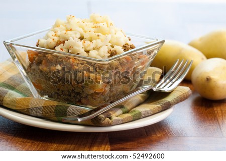 A single serving of Shepherd\'s Pie set against potatoes