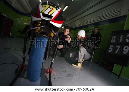 VALENCIA, SPAIN - FEBRUARY 11: Participants in the Moto2 and 125cc Test - Dominique Aegerter with white cup looking his motorbike - on February 11, 2011 in Cheste, Valencia, Spain