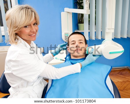 woman dentist examine male patient teeth with x-ray machine