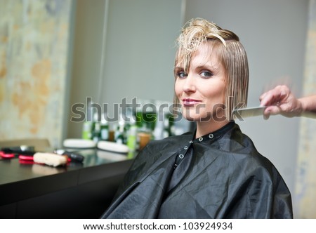 attractive woman in hair salon with cut hair on her shoulder
