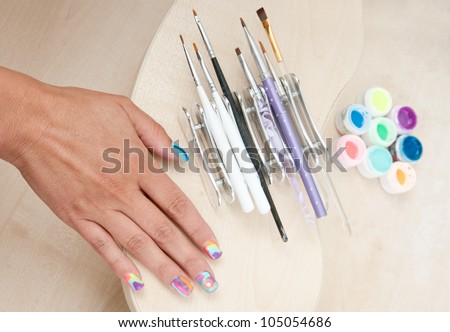 woman manicured painted nails with set of manicure tool brushes and paints