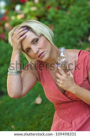 woman feeling hot and holding water bottle outside in the city park