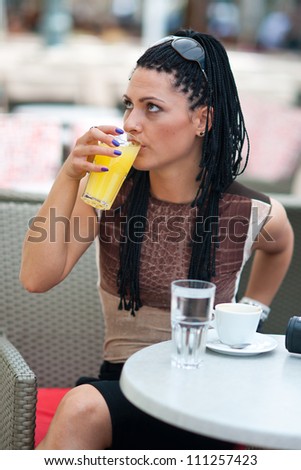 woman drinking orange juice in bar terrace