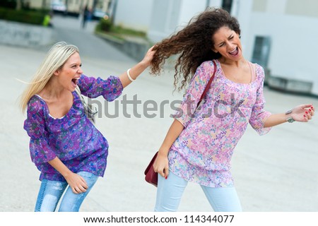 two woman fight in the street and pulling hair