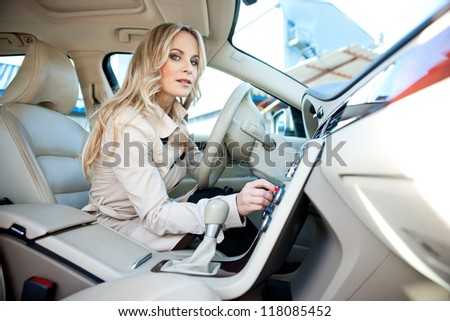 attractive woman in car driver seat adjusting radio