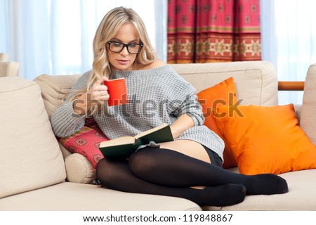 attractive woman with book in her home sofa