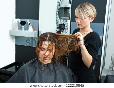hair stylist drying woman hair with hair dryer in salon