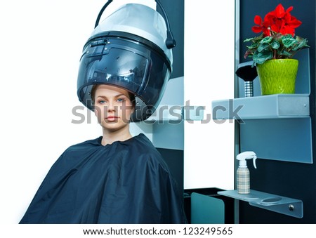 attractive woman using hair dryer in hairdresser salon
